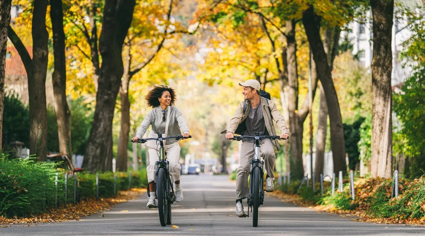 Deux cyclistes roulent dans une allée d'arbres en automne